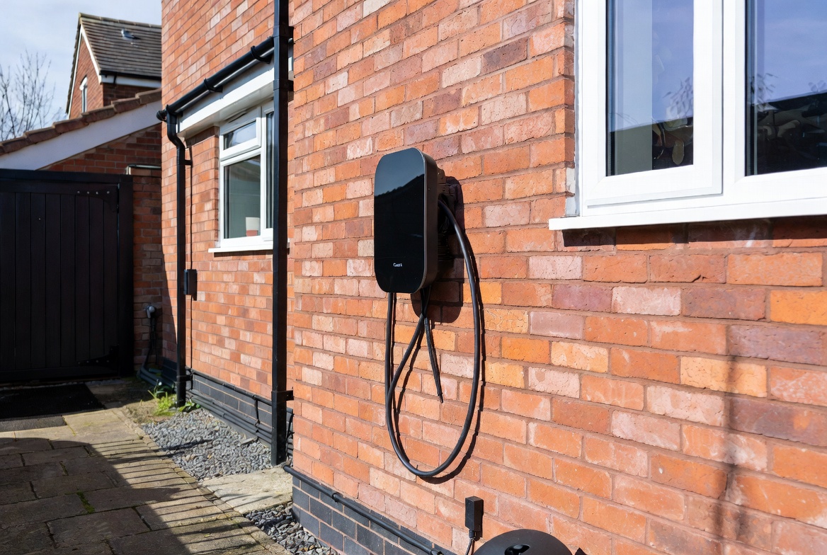 Home EV charger UK installed on garage wall next to electric car