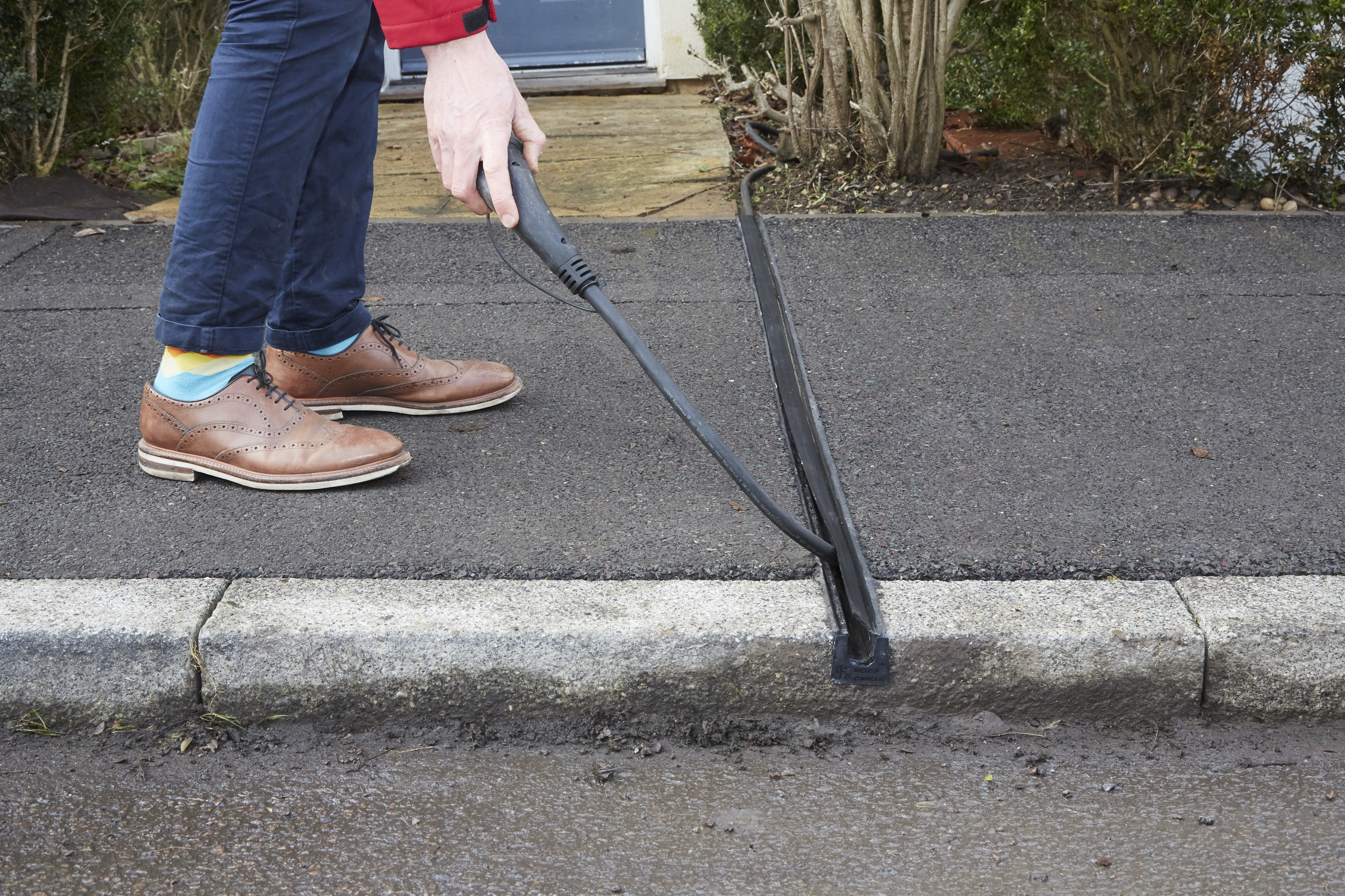 Kerbo Charge cable channel set into a UK pavement, carrying an EV charging cable from a house to a car parked on the street